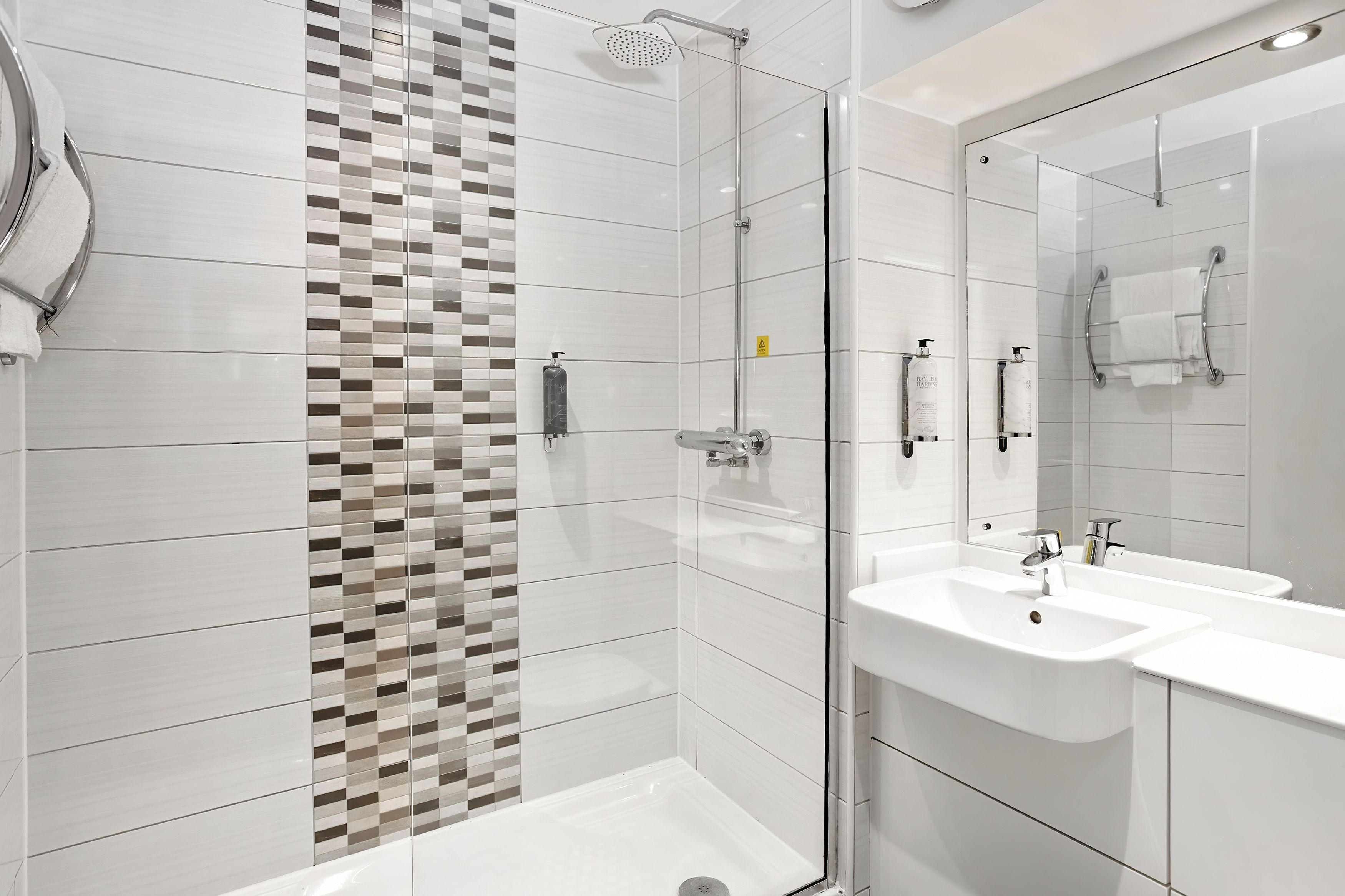 Een moderne badkamer met een douche, twee wastafels en een grote spiegel.