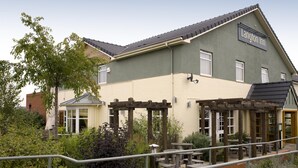 En bygning med et skilt, der siger 'Langton Inn', et overdækket udendørs siddeområde og en have med forskellige planter.