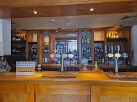A bar area with multiple taps, shelves stocked with bottles, and a food allergy sign.