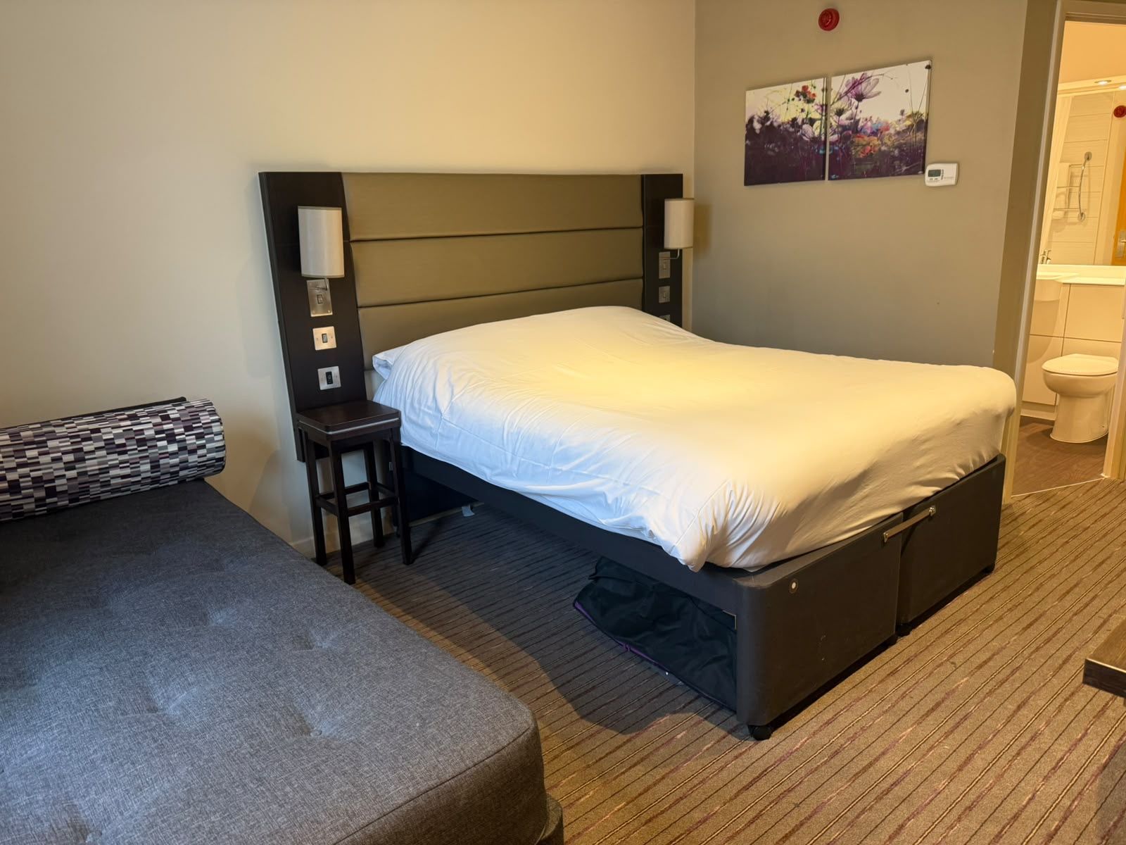 A hotel room with a bed, a small table, a chair, and a sofa.