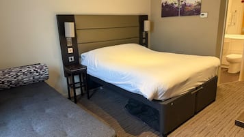 A hotel room with a bed, a small table, a chair, and a sofa.