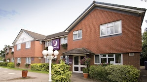 Een hotel met twee verdiepingen, een bakstenen gevel, een klein portaal en een bord met de tekst Premier Inn.