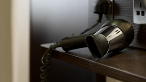 A hair dryer on a wooden surface with a power outlet in the background. - Premier Inn Runcorn (Runcorn)