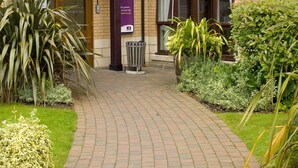 Entree van een Premier Inn hotel met een bakstenen gevel, een gebogen pad en omliggend groen.