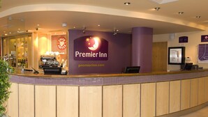 A hotel reception area with a counter, a coffee machine, and a sign for Premier Inn. - Premier Inn Reading Central (Reading)