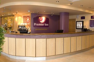 A hotel reception area with a counter, a coffee machine, and a sign for Premier Inn.