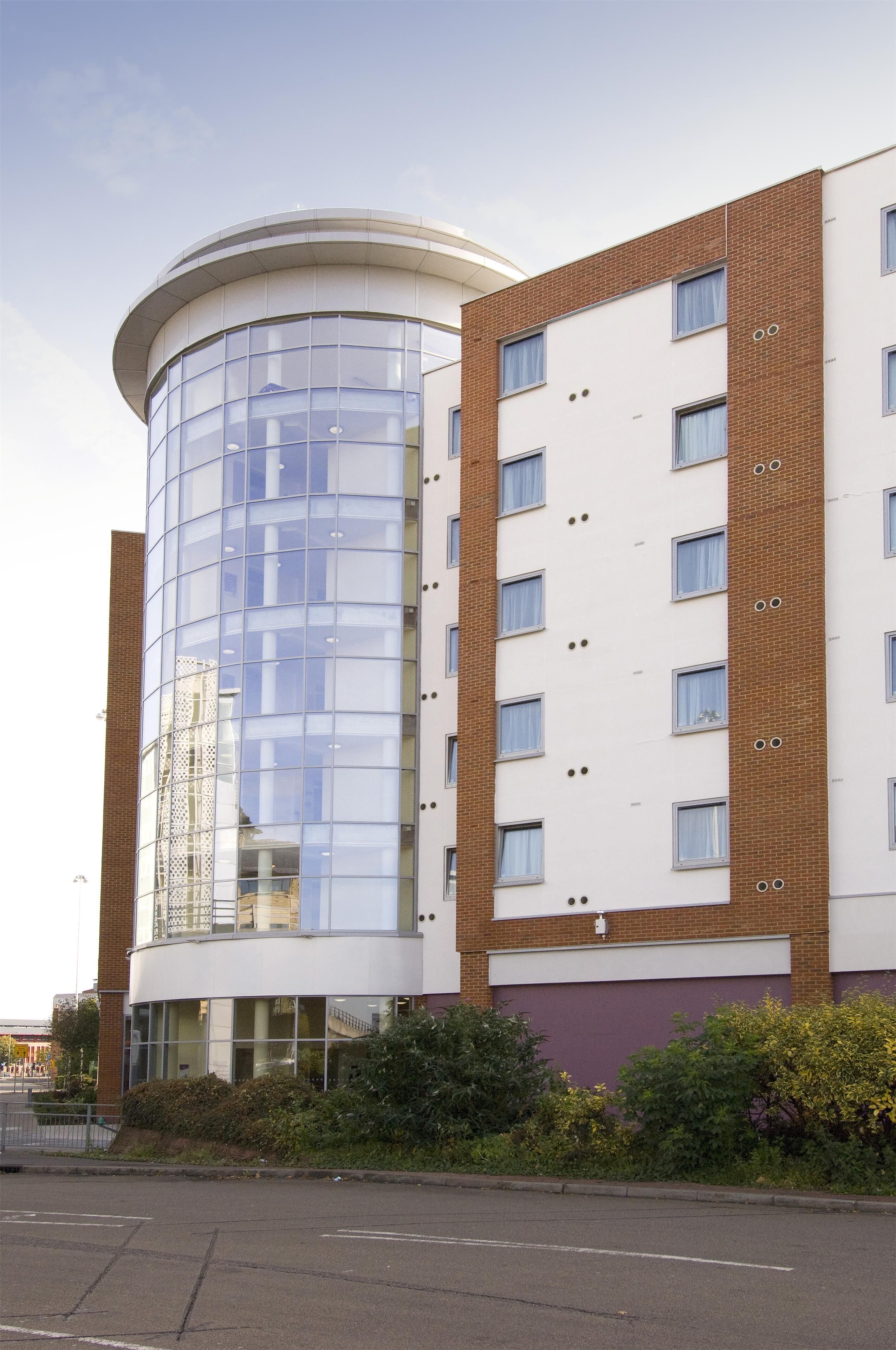 A modern building with a cylindrical glass section and a brick facade.