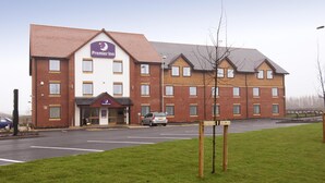 Een Premier Inn hotel met een bakstenen gevel, meerdere ramen en een parkeerplaats.