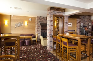 A restaurant with brick walls, wooden furniture, and a patterned carpet. - Premier Inn Widnes (Widnes)