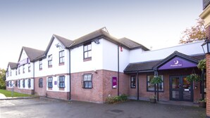 A hotel with a white and brick facade, a prominent Premier Inn sign, and a parking lot in front. - Premier Inn Manchester Airport Heald Green (Cheadle)