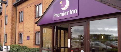A Premier Inn hotel with a brick facade, large windows, and a purple awning.
