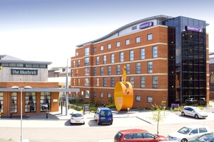 Un hotel con una llamativa escultura amarilla, un edificio moderno de vidrio y un letrero que dice 'The Bluebrick'.