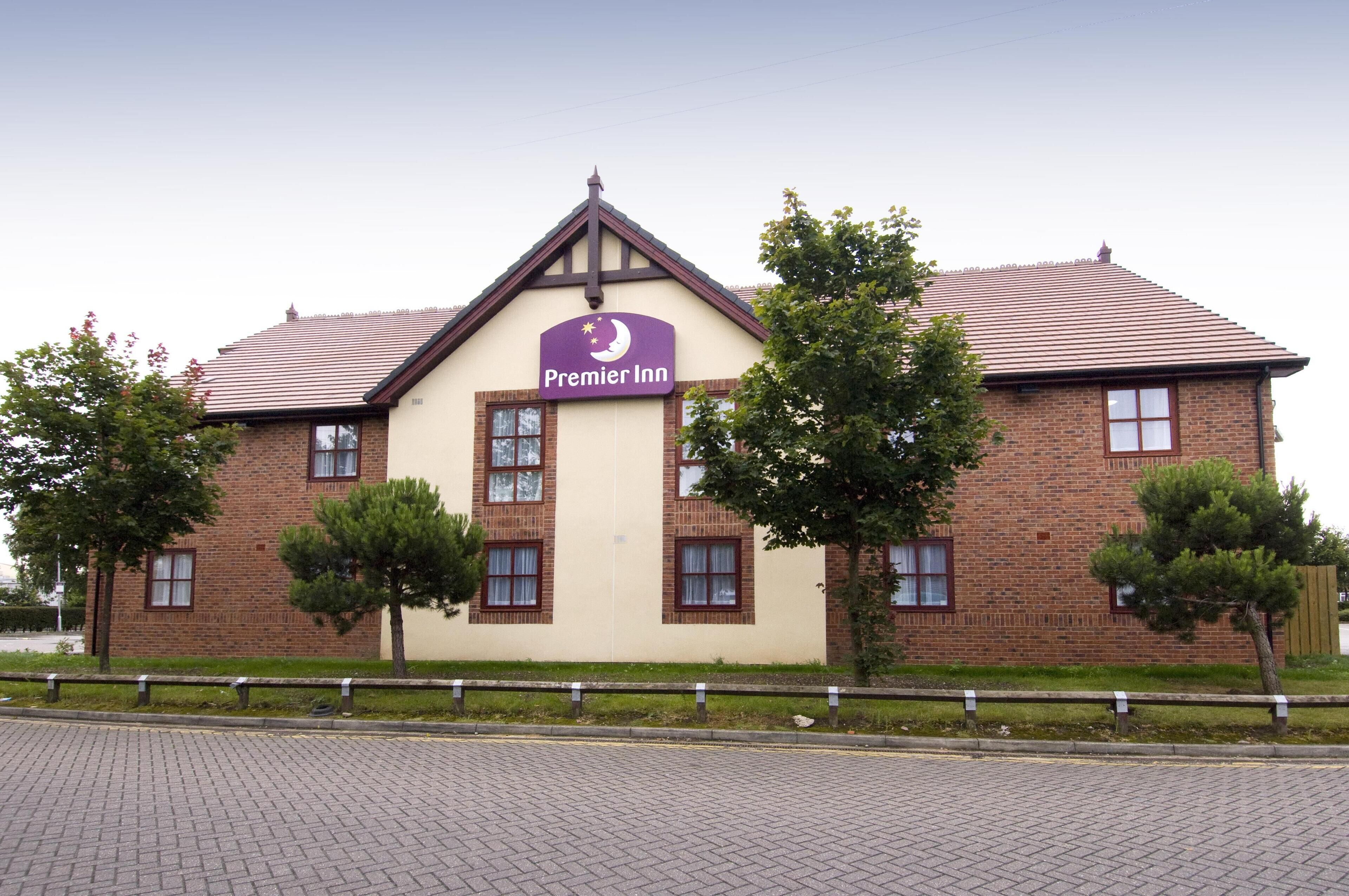Un bâtiment en briques avec une enseigne « Premier Inn », doté d’un toit à deux versants et de nombreuses fenêtres.