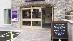 The exterior of a Premier Inn hotel with a stone facade, large glass entrance, and a sign welcoming guests to the Kendal Central Premier Inn. - Premier Inn Kendal Central (Kendal)