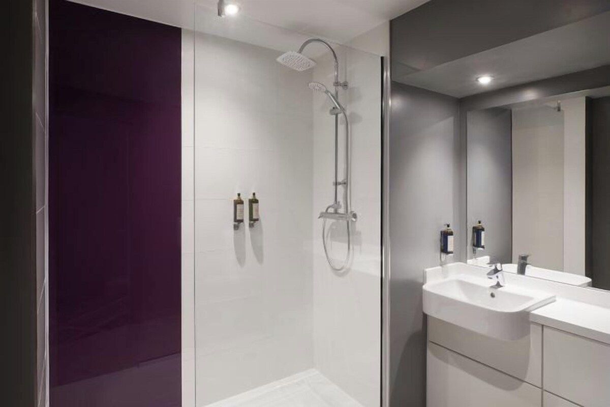 Une salle de bain moderne avec une douche à parois de verre, un lavabo blanc et un grand miroir.