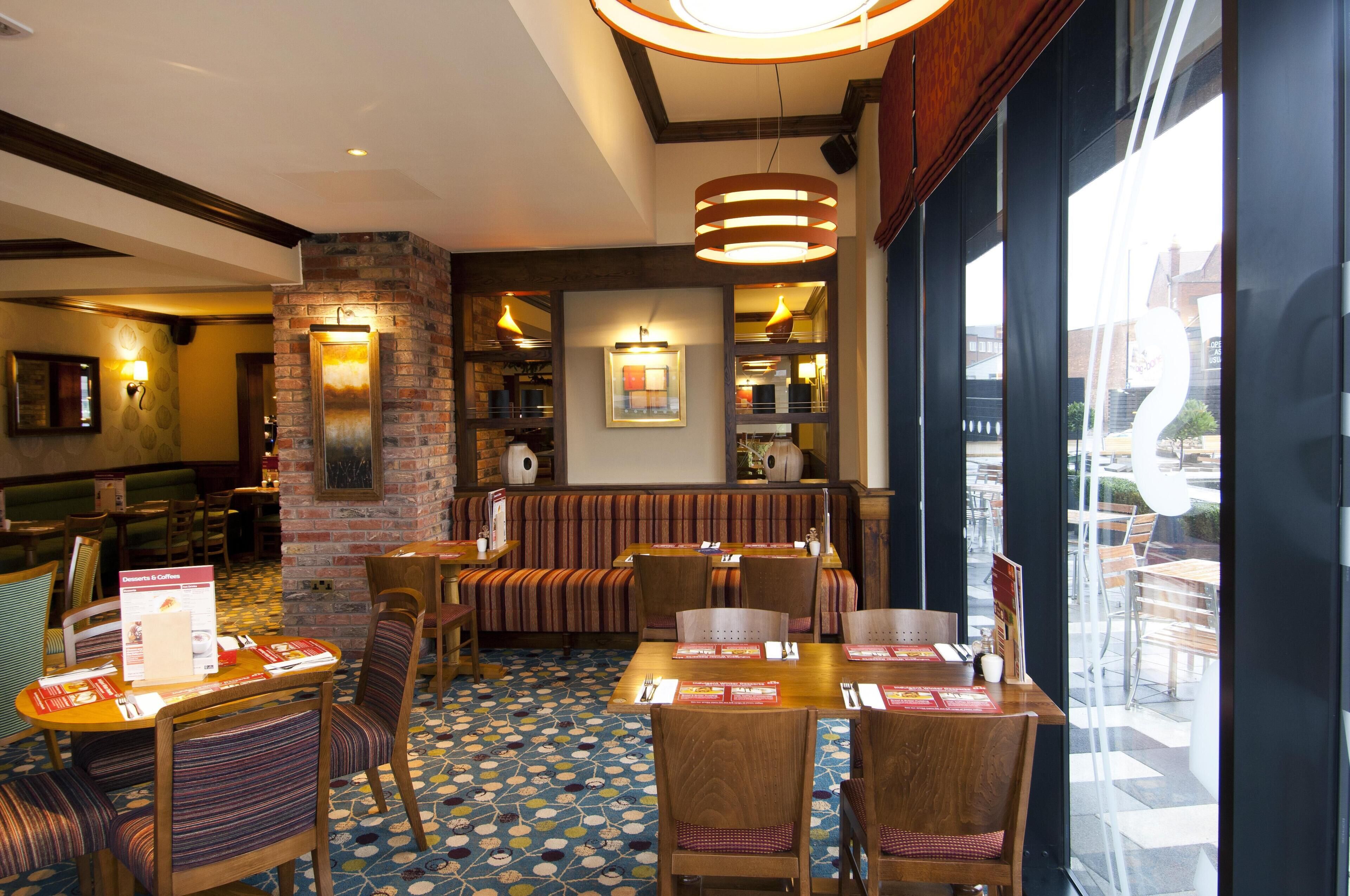A restaurant with booths, tables, and chairs, a patterned floor, and a brick wall.
