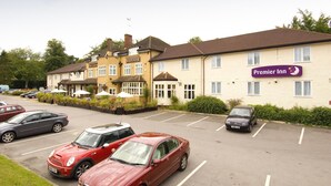 A hotel with a sign for 'Premier Inn' and a parking lot with several cars. - Premier Inn Bagshot (Bagshot)