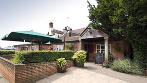 A brick building with a green umbrella, potted plants, and a signboard. - Premier Inn Swindon North (Swindon)