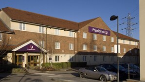 Un hotel Premier Inn con fachada de ladrillo, un cartel y un aparcamiento con coches.
