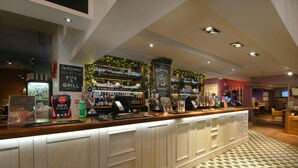 A bar area with a counter, shelves of bottles, and a sign for a pub and grill. - Holmfield Arms By Greene King Inns (Wakefield)