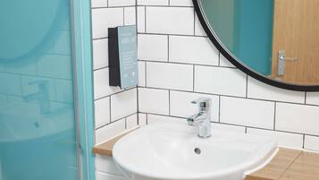 Un baño con un lavabo blanco, un espejo y un dispensador de jabón en la pared.