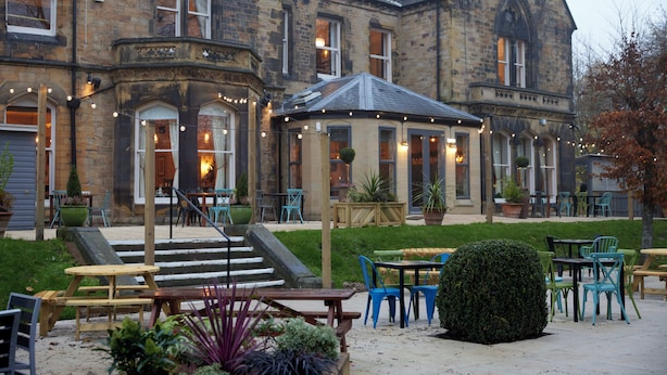 A historic building with a courtyard, outdoor seating, and a well-maintained garden. - Holmfield Arms By Greene King Inns (Wakefield)