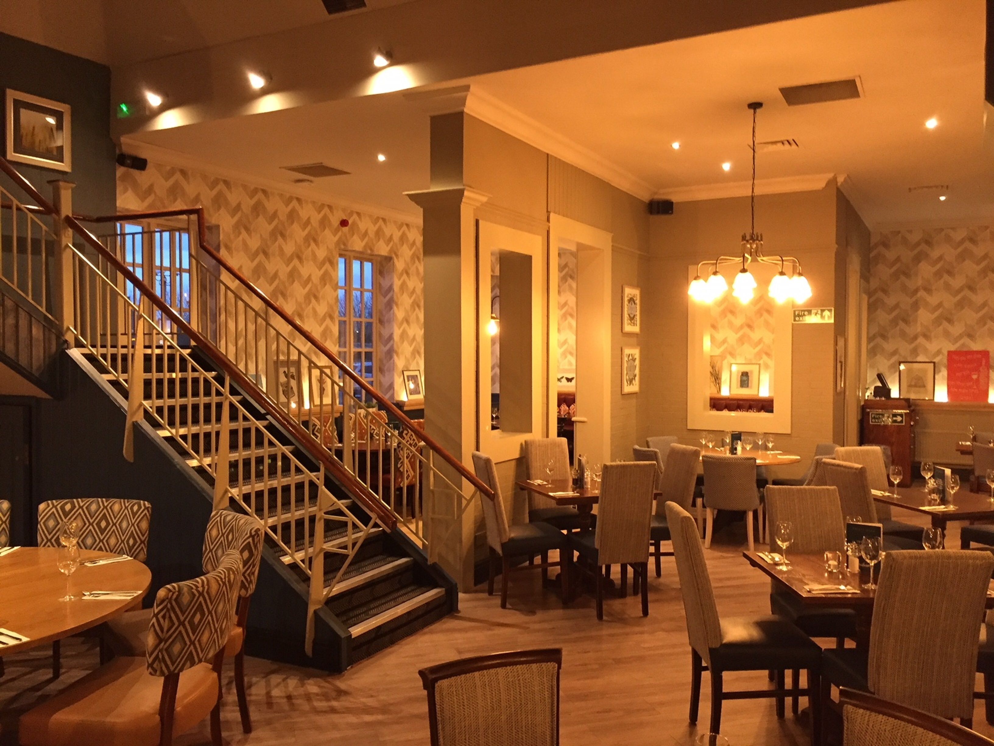 Un vestíbulo de hotel con una escalera, zona de comedor y bar.