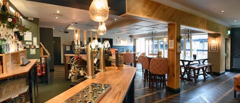 A bar area with wooden countertops, hanging lights, and a patterned floor.