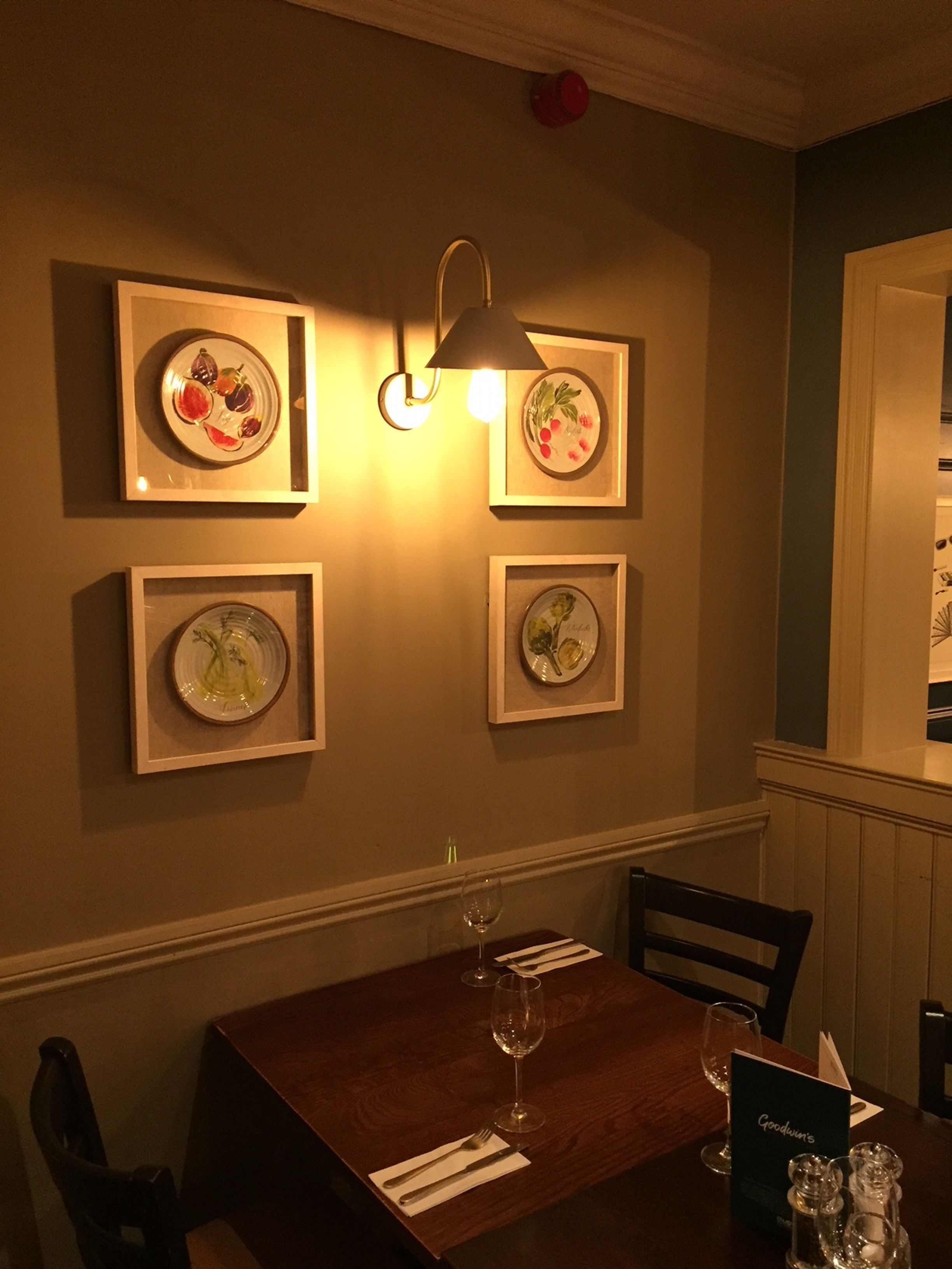 A dining area with a wooden table, chairs, and framed artwork on the wall.
