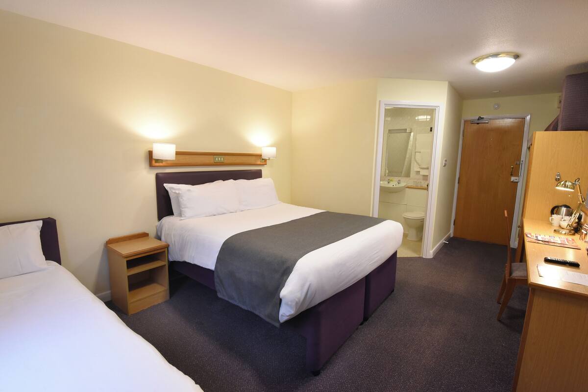 Ein Hotelzimmer mit Bett, Nachttischen, einem Schreibtisch und einem Kleiderschrank.