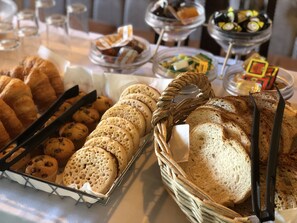 A buffet table with various baked goods including croissants, muffins, and bread. - The Mount By Greene King Inns (Wigan)