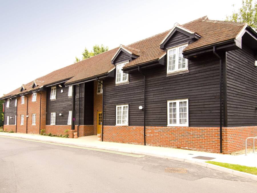 A two-story building with a brick base and black upper walls, featuring multiple windows and a door.