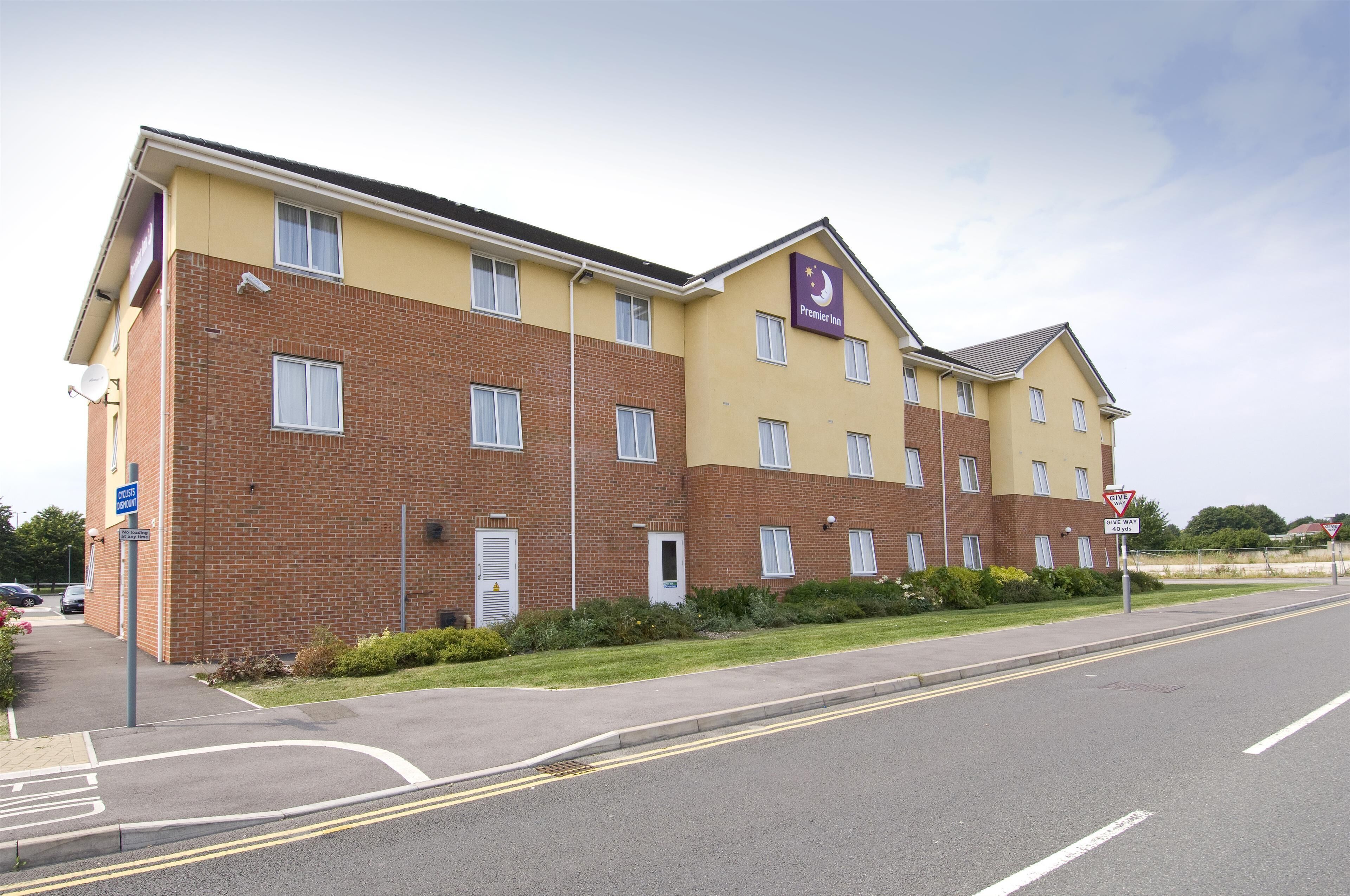 Um hotel de vários andares com fachada de tijolos, várias janelas e uma placa indicando Premier Inn.