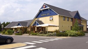 A Kembrey Inn with a blue and yellow exterior, outdoor seating, and a crosswalk in front. - Premier Inn Swindon Central (Swindon)