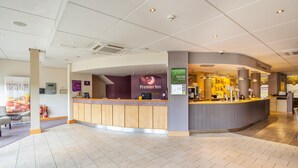 Un'area reception di un hotel con un bancone, un cartello con la scritta Premier Inn e un ristorante Thyme.