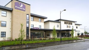 Un hotel Premier Inn con facciata in mattoni, un ristorante specializzato in bistecche e una curata area giardino.