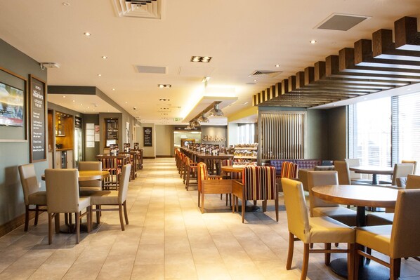 A spacious restaurant with multiple dining areas, a staircase, and a view of the city.