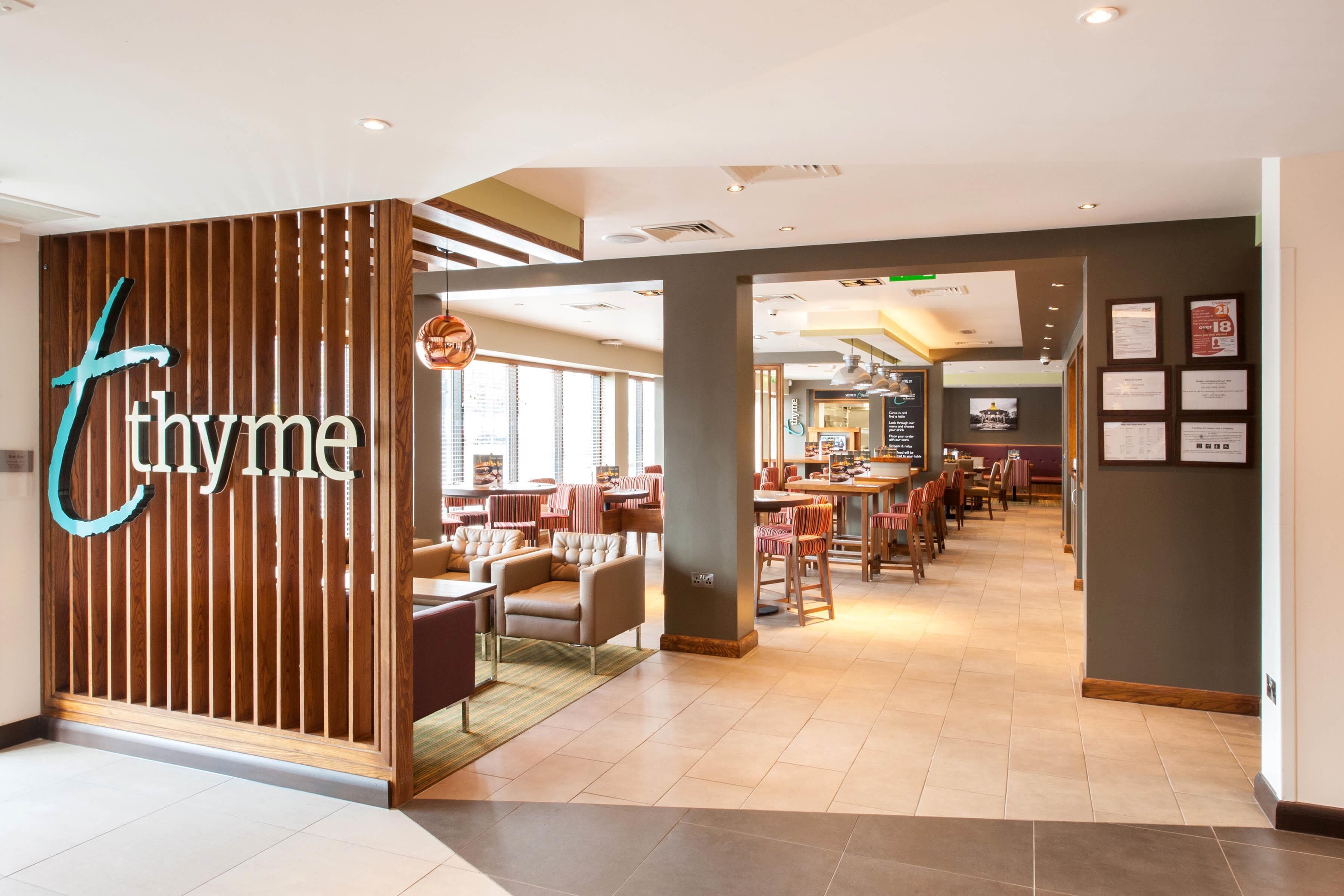 A hotel lobby with a reception desk, seating area, and a view of the dining area.