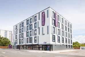 A modern hotel building with multiple floors, large windows, and a prominent Premier Inn sign.