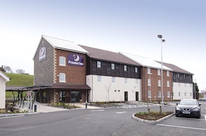 Un hotel Premier Inn con fachada de ladrillo, un acceso cubierto y un área de estacionamiento.