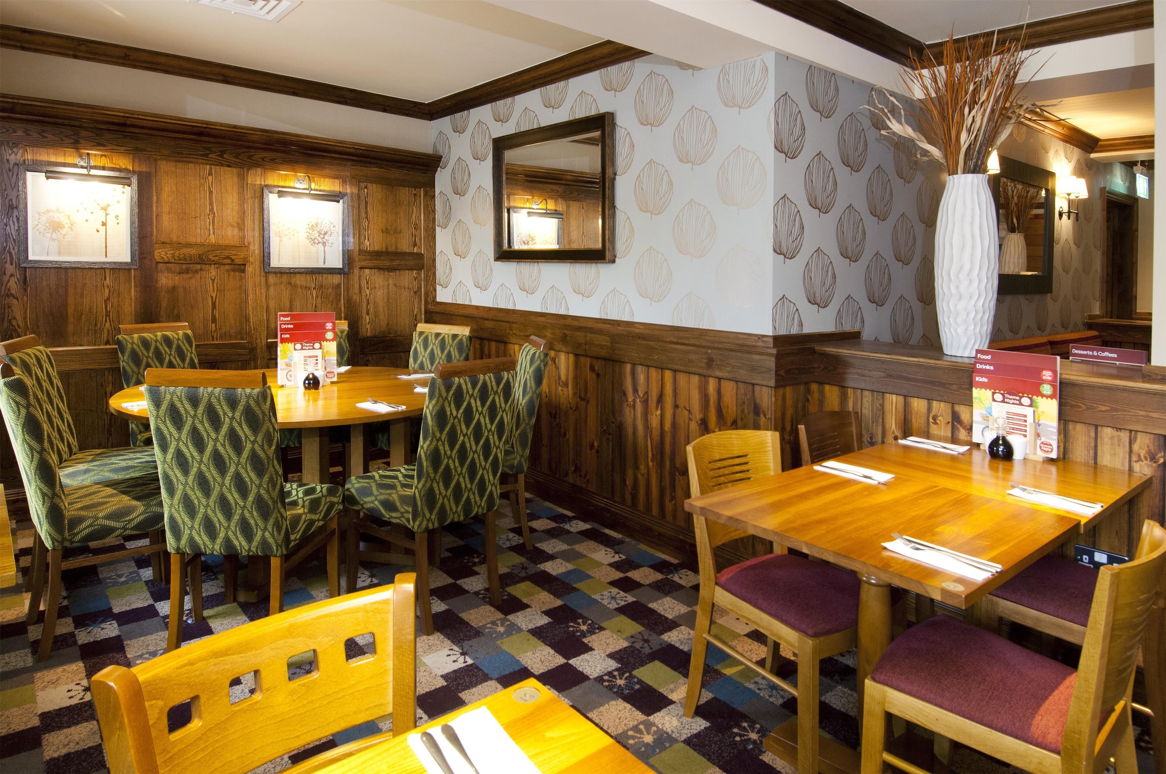 A restaurant with wooden paneled walls, patterned wallpaper, and a checkered floor.