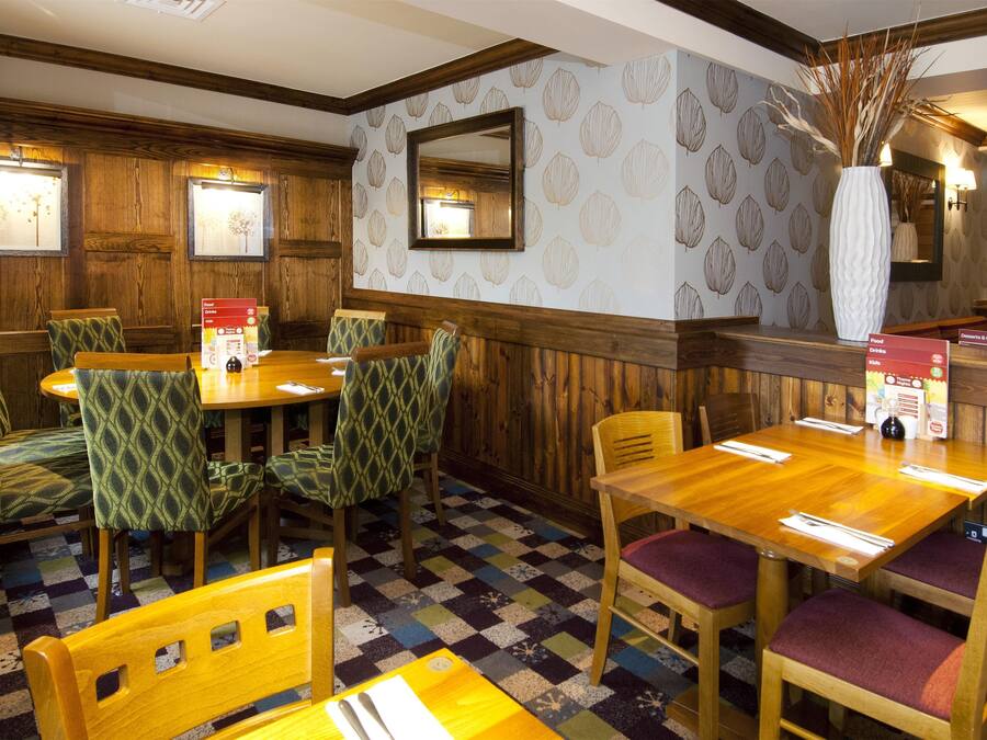A restaurant with wooden paneled walls, patterned wallpaper, and a checkered floor.