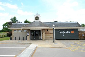 A building with a clock tower, a sign for 'Mill Lodge,' and a 'Beefeater' sign on the side. - Premier Inn Lincoln - Canwick (Lincoln)