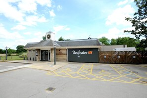 A building with a clock tower, a garage door with a logo, and a parking lot with yellow markings. - Premier Inn Lincoln - Canwick (Lincoln)