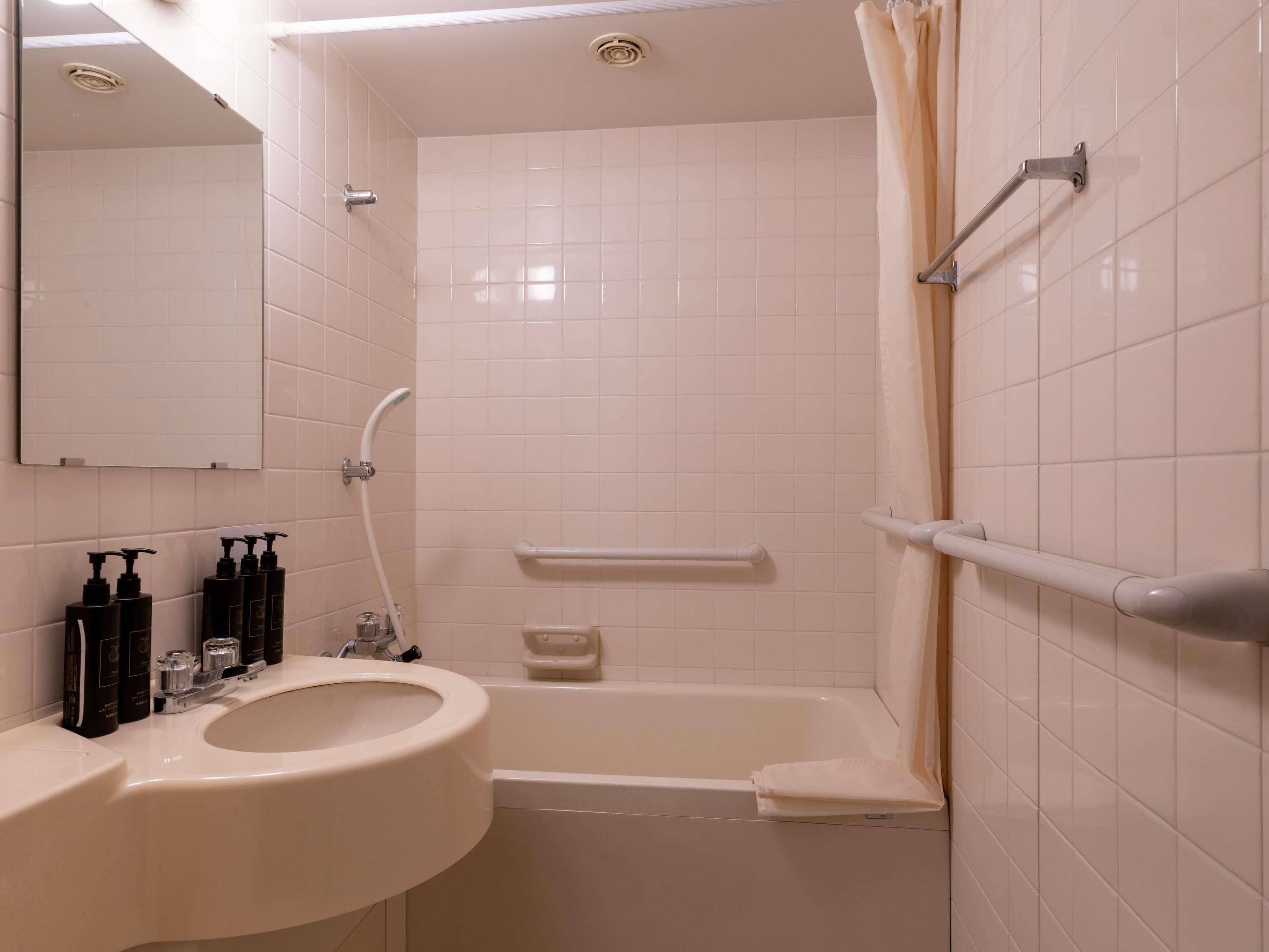 A bathroom with a sink, mirror, shower, and toilet.