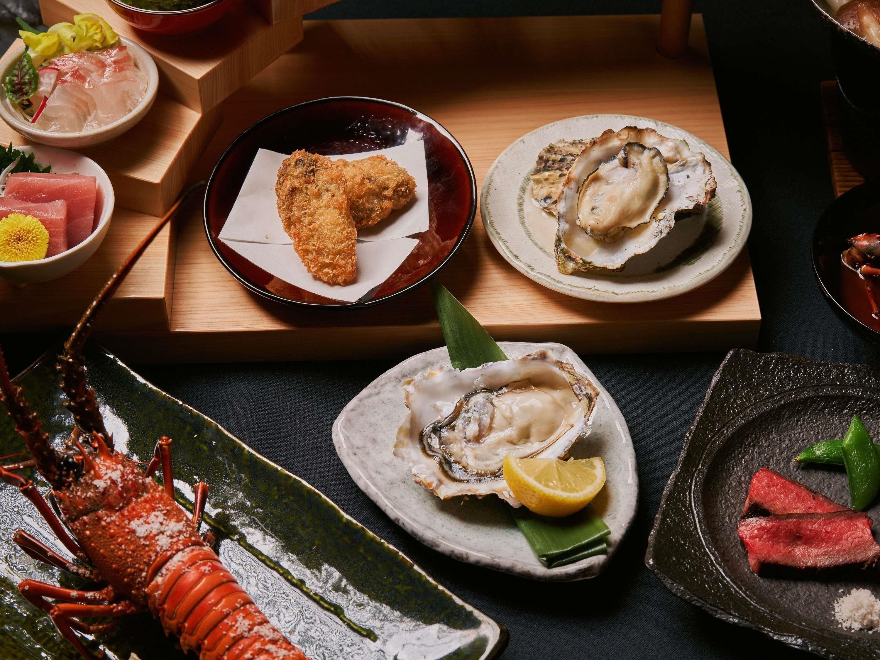 A variety of seafood dishes on a wooden table, including oysters, a lobster, and other seafood items.