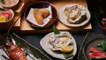 A variety of seafood dishes on a wooden table, including oysters, a lobster, and other seafood items.