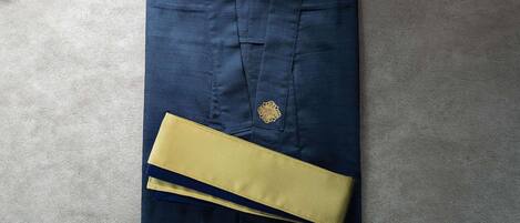 A folded dark blue shirt with a gold emblem and a yellow cufflink on a textured surface.