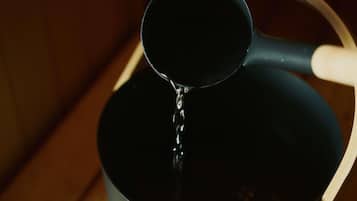 A black bucket with a handle and a ladle pouring liquid into it.