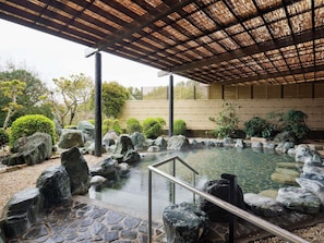 A traditional Japanese-style hot spring with a stone pathway, a wooden pergola, and surrounding greenery. - Grand Mercure Ise-shima Resort & Spa (Shima)